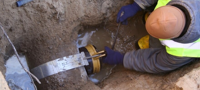 Crew tapping a city sewer main in an open trench